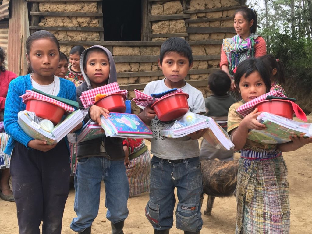 4 niños con material escolar en Guatemala